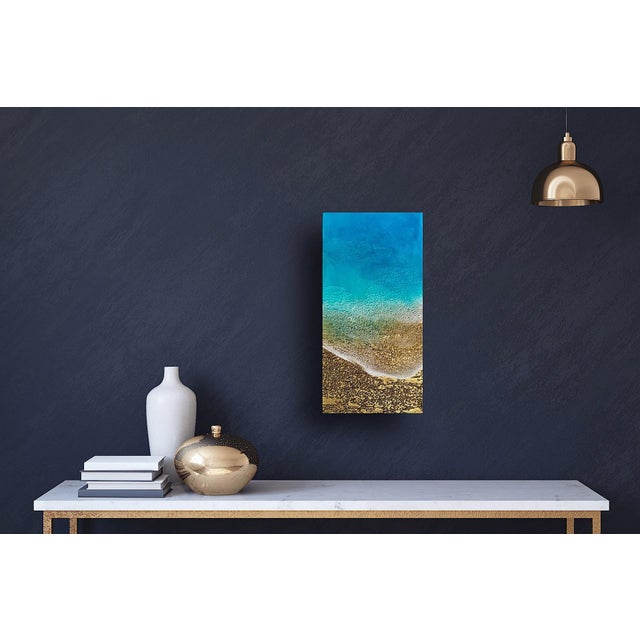 This mixed media piece on wood panel captures a serene coastal scene, where vibrant blues transition into golden sandy...
