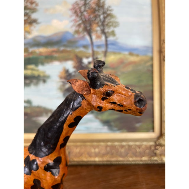 This hand-carved wooden giraffe sculpture is a finely crafted decorative piece showcasing artisanal folk art traditions....