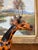 This hand-carved wooden giraffe sculpture is a finely crafted decorative piece showcasing artisanal folk art traditions....