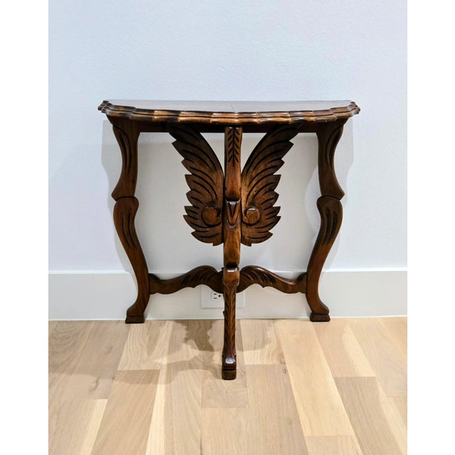 Elevate your space with this striking demi-lune accent table, crafted from solid wood and featuring beautiful carved...