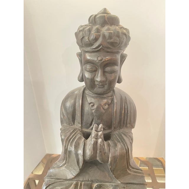 Heavy and large a wooden Buddha statue, specifically a seated figure in a meditative pose with hands clasped in prayer...
