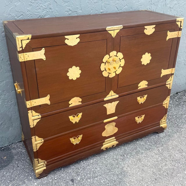 A striking vintage Chinese-inspired highboy armoire, masterfully crafted in rich warm wood tones and adorned with...