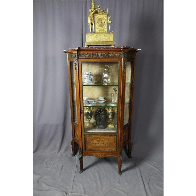 Showcase in marquetry of native wood inverted curves on the sides. It has its original shelves and its patina. A marble...