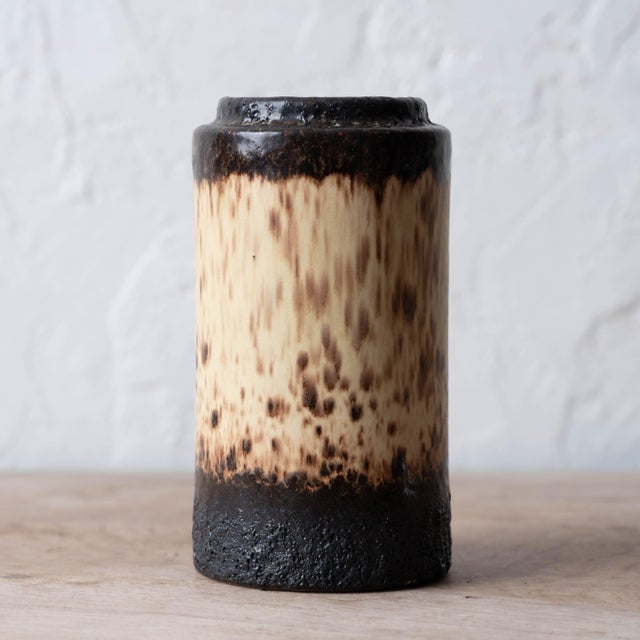 A West German fat lava vase in cylindrical form, glazed in a heavy dripping brown, cream, and black volcanic glaze, circa...