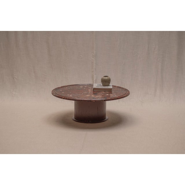 Elegant mid-century coffee table featuring a beautifully figured red marble top resting on a substantial cylindrical...