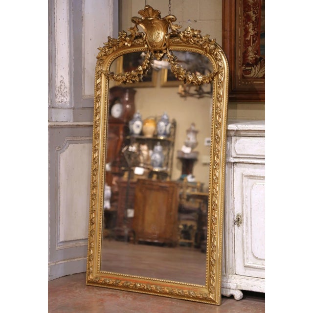 Crafted in France circa 1860, this impressive antique Louis XVI giltwood mirror is distinguished by its tall arched form,...