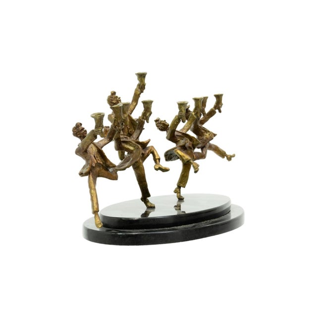 A whimsical bronze menorah by renowned sculptor Zachary Oxman featuring a lively procession of dancing figures, each...