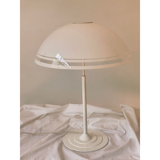 A generously sized, minimalist table lamp in a postmodern design. Slender base made of white lacquered metal, large,...
