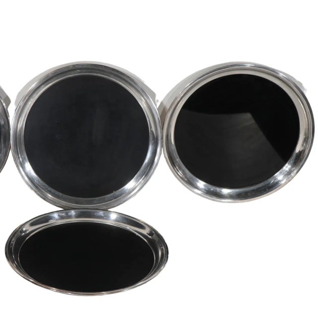 Offering four Mid Century, Art Deco serving trays, each with a silver plated, or chrome rim, and a chic black laminate...