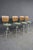 Set of four mid-century modern bar stools featuring sculpted slatted walnut backs, olive green upholstered seats, and...