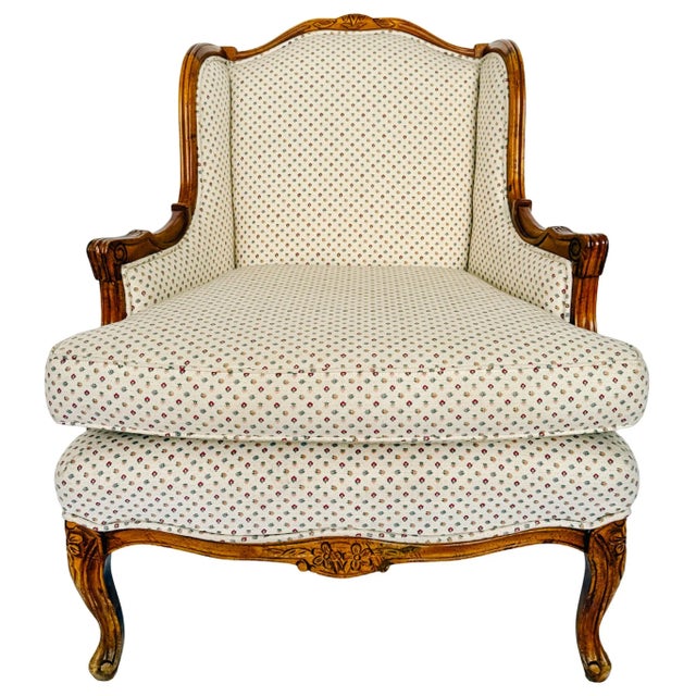 An elegant vintage French Provincial Louis XV armchair featuring an exposed, carved wood frame with graceful cabriole legs...
