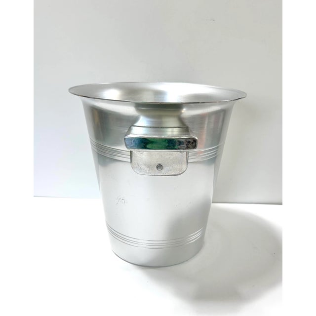 A classic vintage French champagne bucket crafted in brushed aluminum with traditional side handles and understated banded...