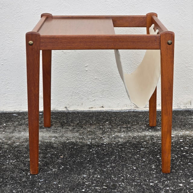Simple and stylish, this Danish mid-century modern side table features a sleek magazine rack built into one side to keep...
