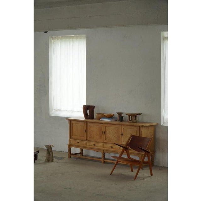 A charming low-profile sideboard crafted in oak and designed in the style of Henning Kjærnulf, Denmark, 1960s. The piece...