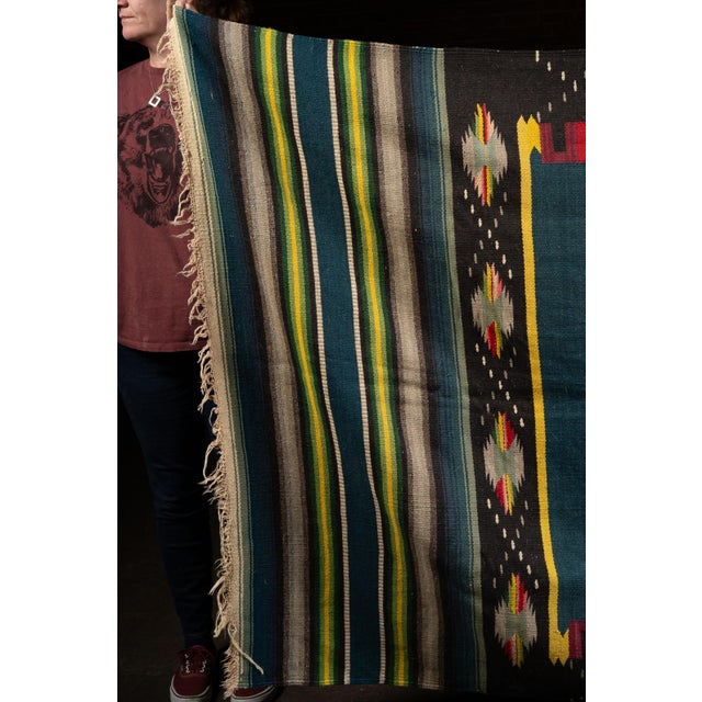 Handwoven Mexican serape blanket featuring a bold Southwestern-inspired geometric medallion centered within a deep...