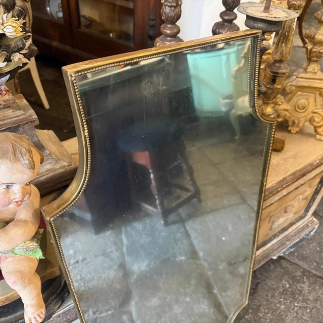 A shield shaped brass wall mirror designed and manufactured in Italy in the Sixties in the style of Giò Ponti, it's in...