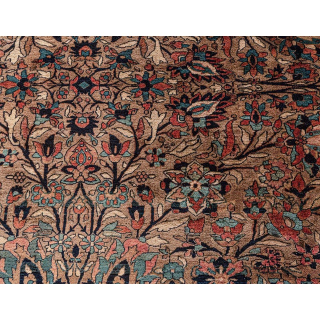 A hand-knotted wool antique Persian rug dating back to circa 1900. An allover stylized floral design in aqua-blue, brown...