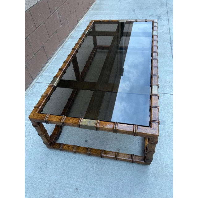 Asian influenced faux bamboo with brass clad accented base, having thick smoked glass inset top, made by Drexel Heritage,...