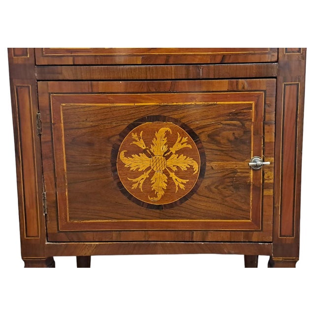 Veneered bedside table in walnut wood. Front with a door and drawer placed under the top. High truncated pyramidal feet...