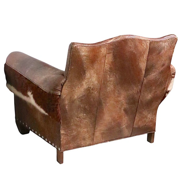 Impressive leather, and fur upholstered club and with studded nailhead trim, with matching footrest ottoman. The chair is...