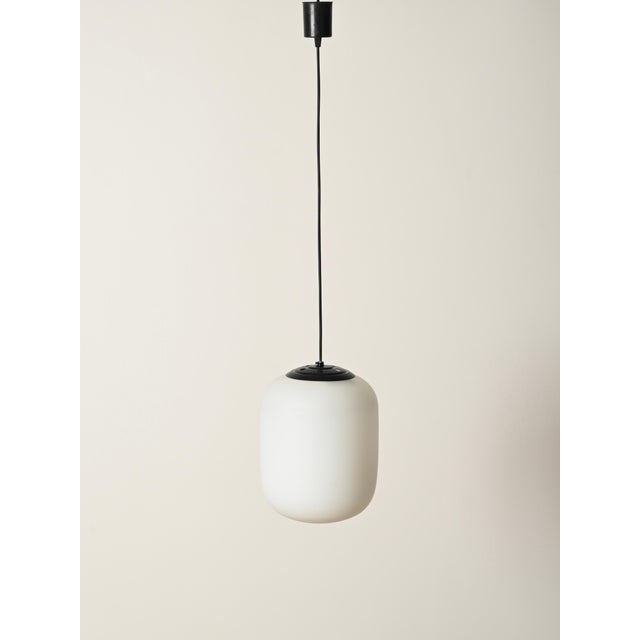 Stunning and unique pair of mid-century pendant lamps in opaline glass and black lacquered metal. This elegant set was...