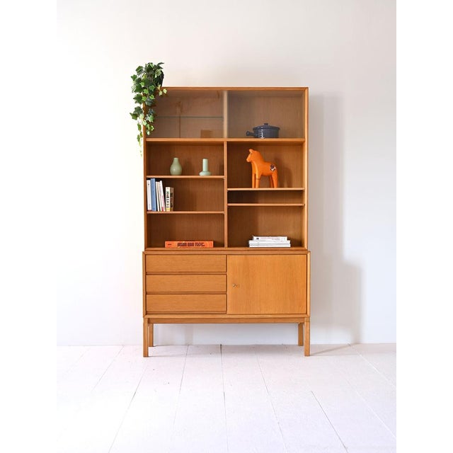 Scandinavian oak bookcase designed by Grabinski in the 1960s with a glass display case, drawers, and a hinged door....