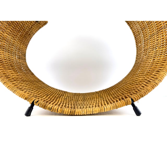 A sculptural mid-century firewood basket dating to approximately the 1960s, finely woven in warm natural rattan over a...