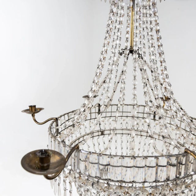 Large ceiling chandelier with six brass candle holders. The hanging of glass prisms, drops and beads is guided over two...