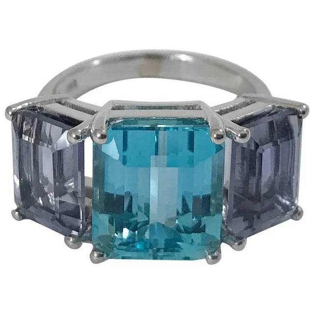 Christina Addison 18kt White Gold Three Stone Emerald Cut Ring with Blue Topaz and Iolite This Bold 18kt White Gold...