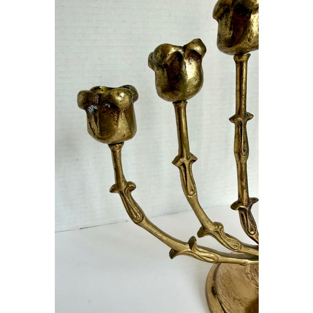 Dating to the mid-20th century, this sculptural brass menorah features rosebud-form candle cups supported by stylized...
