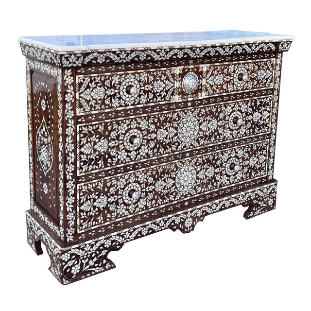 An exceptional handcrafted chest of drawers featuring intricate mother-of-pearl inlay and a natural marble top. Rich...