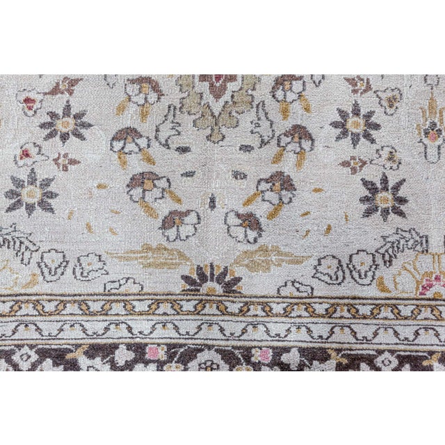 An early 20th century handmade wool Persian Khorassan antique rug. The main field displays blooming florals, leaves and...