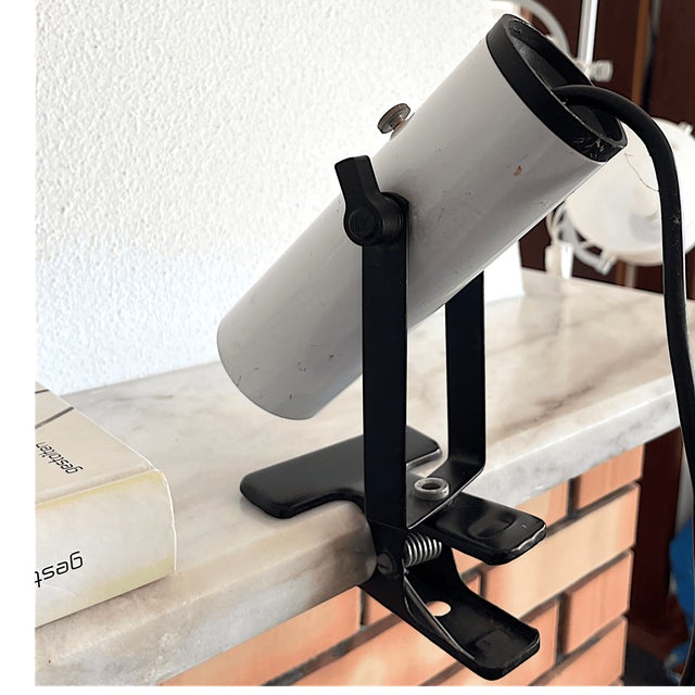 Vintage 1970s white cylindrical metal spotlight clamp lamp in style of Targetti, features an adjustable black metal arm...