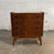 A compact Danish four-drawer commode with warm teak casework, oak accents, and dark round drawer pulls. The piece has a...