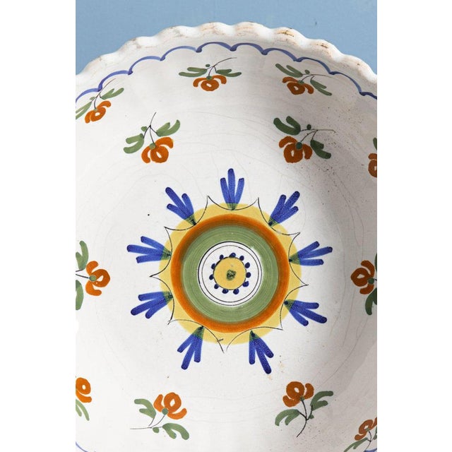 An early 19th-century French faience serving bowl, decorated in blue, green, red, and yellow with a rosette in the centre...