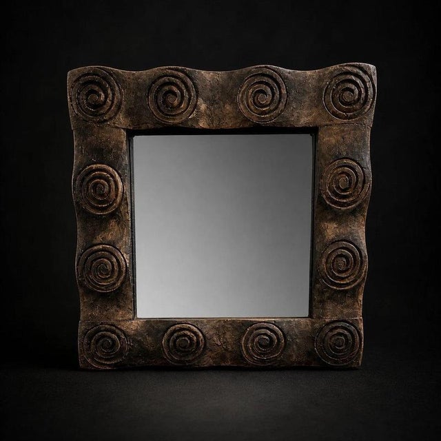 A distinctive hand-carved wooden wall mirror featuring a bold series of raised spiral motifs arranged around a substantial...