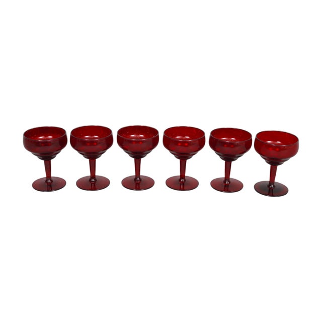 A set of six mid century margarita glasses. Ruby red blown glasses are rippled at the base of the cups, and tapered stems...