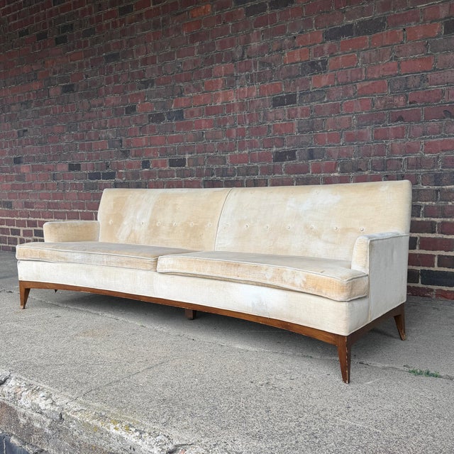 This lovely mid century sofa with wood base has a soft curve, 2 large cushions, a spring back, a single row of button...