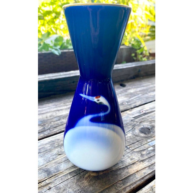 A beautifully proportioned Japanese porcelain vase featuring a graceful hourglass silhouette decorated with a single...
