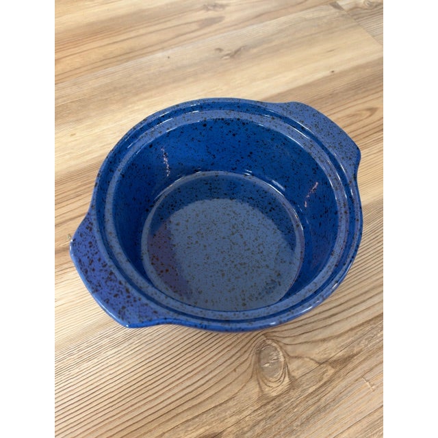 A blue speckled stoneware or ceramic bowl with two side handles, commonly produced by makers like Cerutil or Von Pok &...