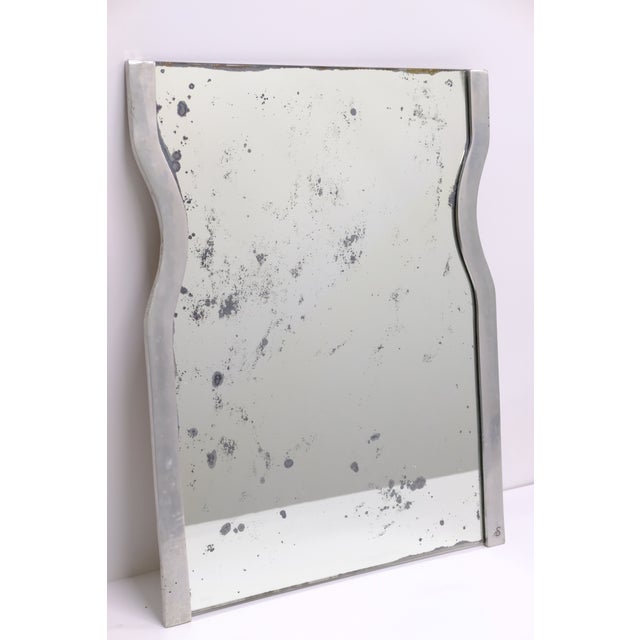 A Brutalist aluminum mirror from the 1970s, with a sculptural cast aluminum frame featuring an organic, wave-like...
