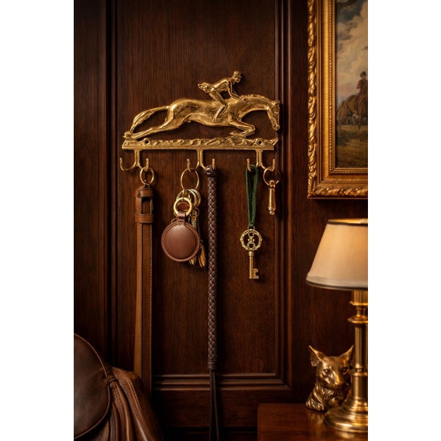 A sculptural vintage brass wall hook rack featuring a classic fox hunt scene, with a rider mid-jump over a galloping horse...