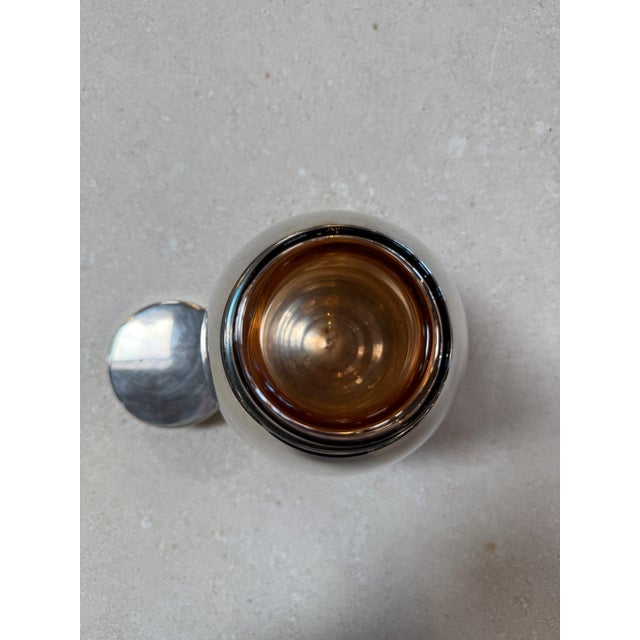 Stylish vintage ice bucket featuring a sleek chrome-plated exterior paired with a warm amber glass liner. The rounded,...