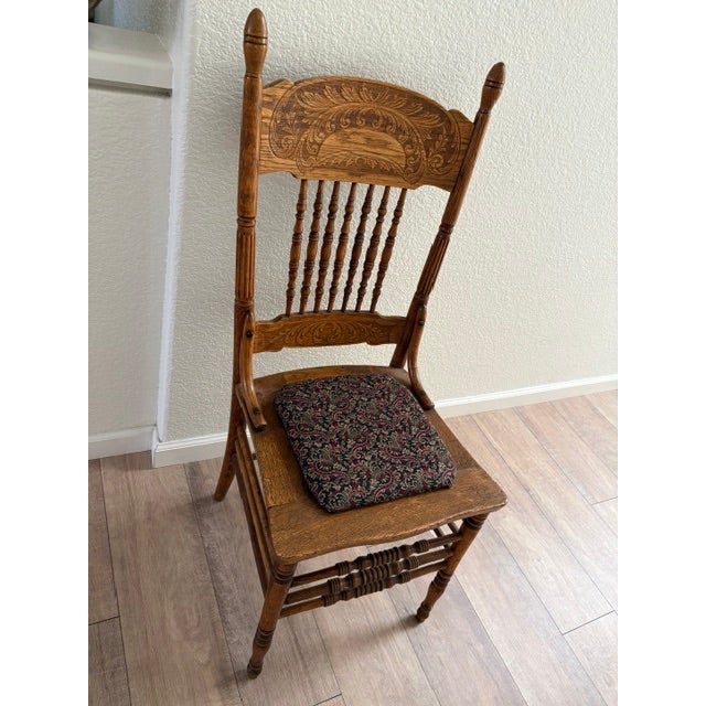 This is a classic turn-of-the-century Americana style pressed-back spindle chair, featuring an ornate faux-carved crest...