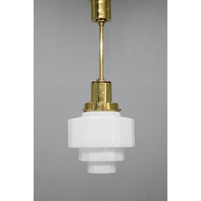 An elegant art deco pendant light produced in czechoslovakia during the 1930s. This vintage chandelier features a brass...