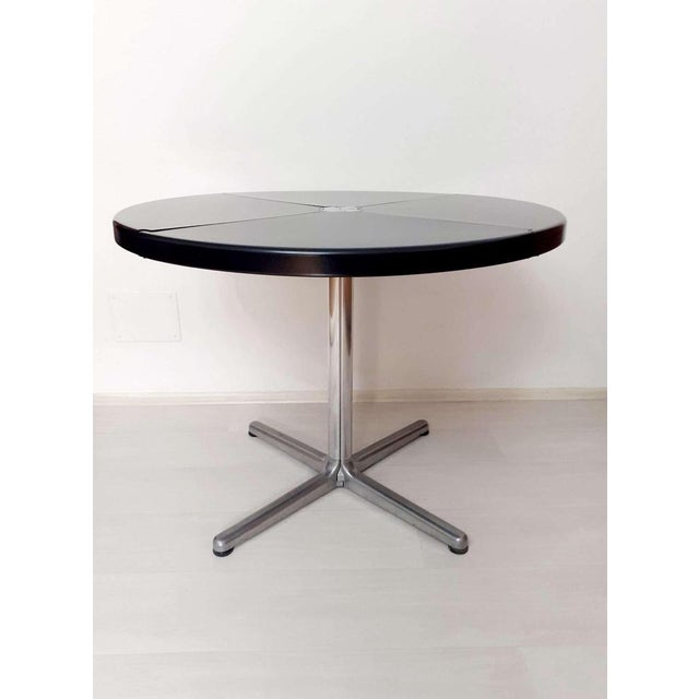 Plano round folding table with four segments, with die-cast aluminum base with wheels and feet and black polyurethane top....