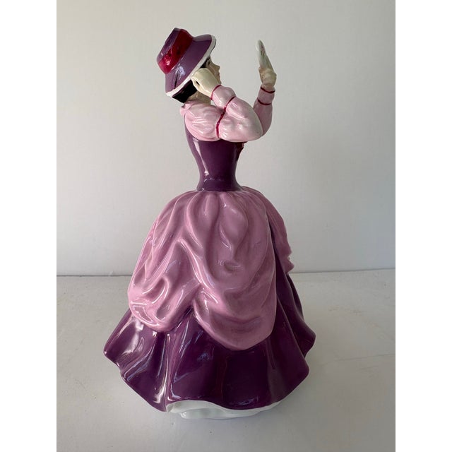 An elegant Royal Doulton porcelain figurine titled “Lady Pamela” (HN 2718), depicting a refined Victorian-era lady...