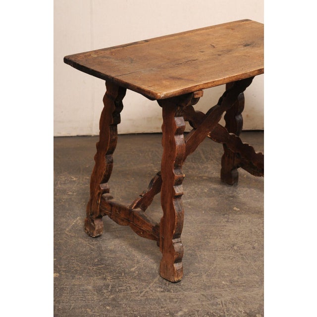 An Italian carved-wood occasional table, with trestle legs and x-stretcher, from the 18th century. This antique table from...