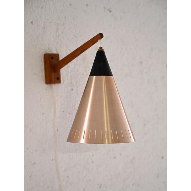 Vintage wall light with wooden arm and black sheet metal and plastic lampshade. A lamp which, thanks to the conical shape...