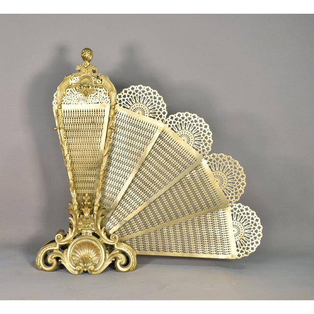 This elegant and ornate peacock fan fire screen concertinas out from a central storage held in place by a pair of brass...